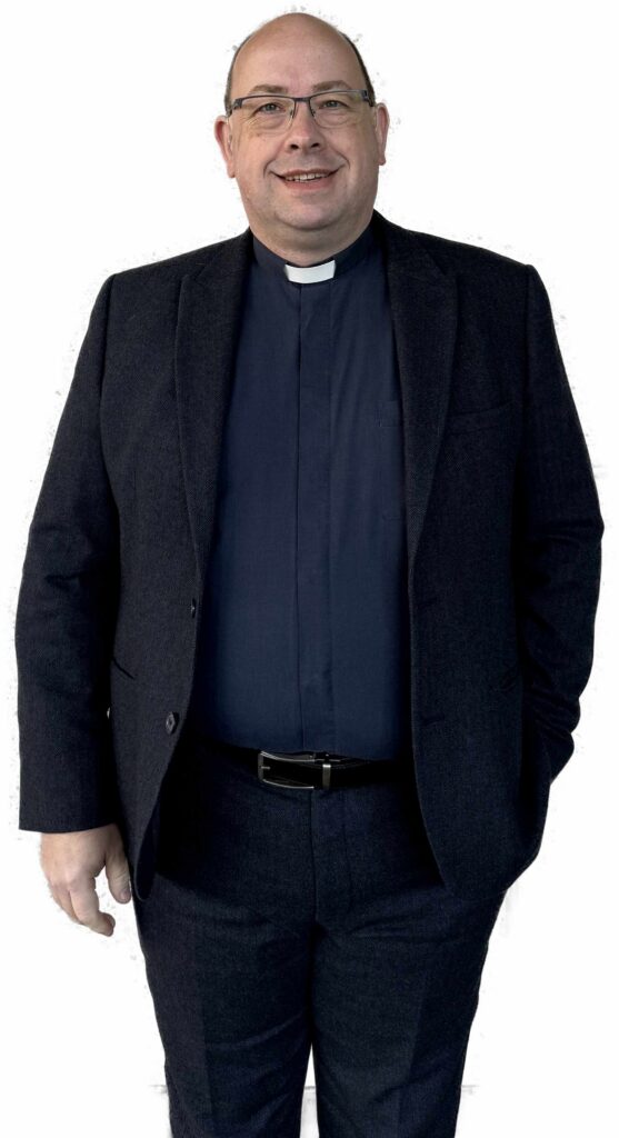 Rev Bryan Kerr standing in a suit, smiling and wearing a ministerial dog collar